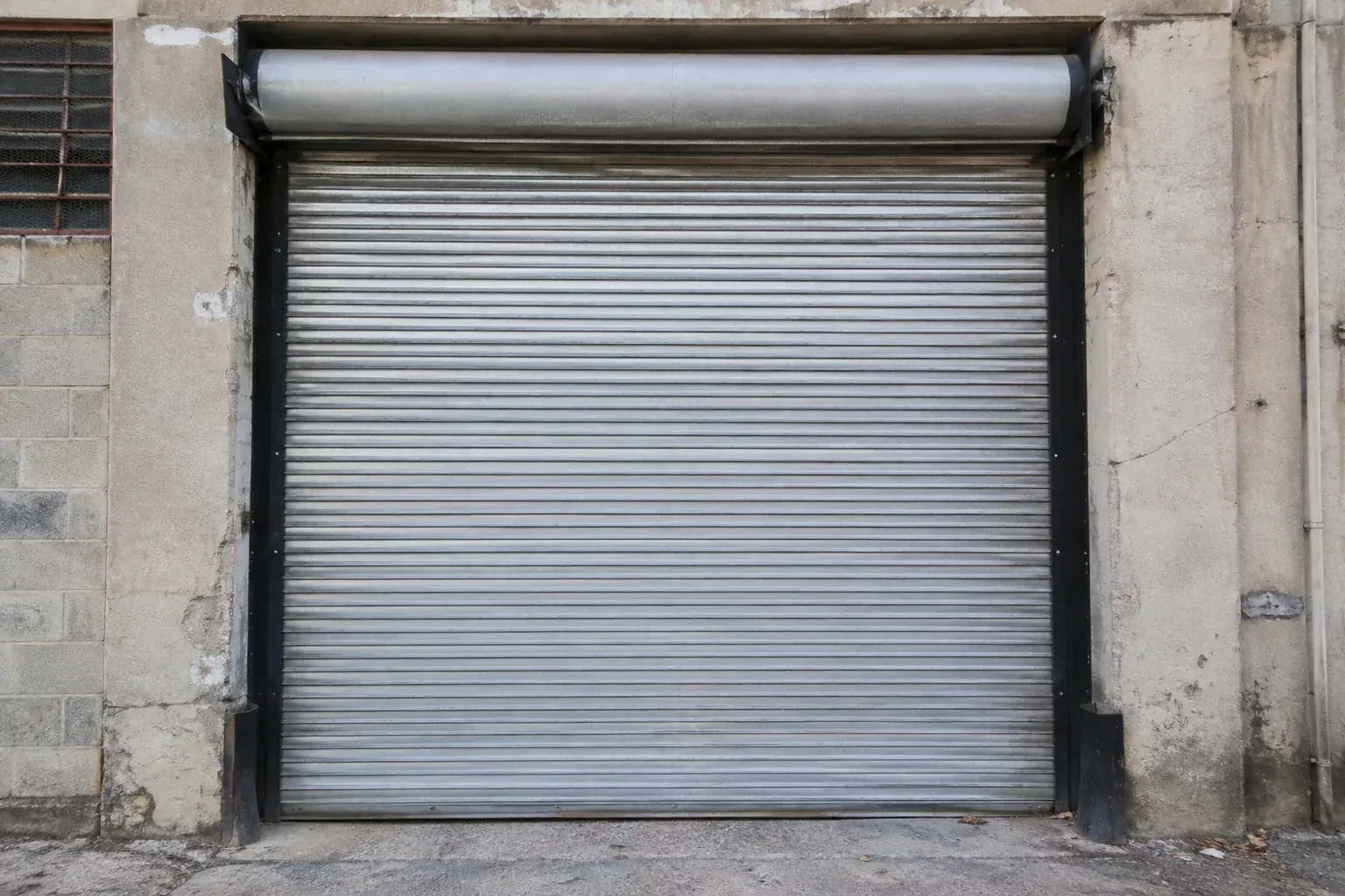 Closed metal rolling shutter in a weathered warehouse opening. — Commercial Rolling Door Repair, Halton Hills